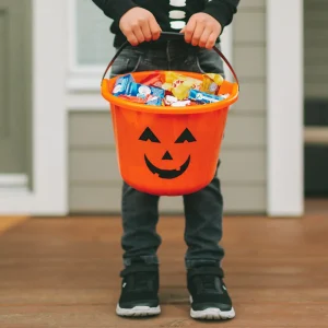 kid holding Halloween bucket full of candy