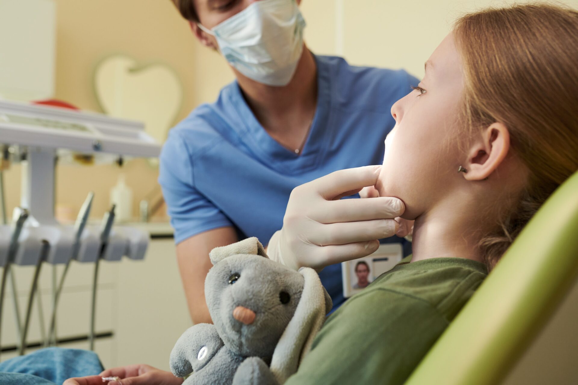 Young girl at a dental checkup with a security stuffed animal