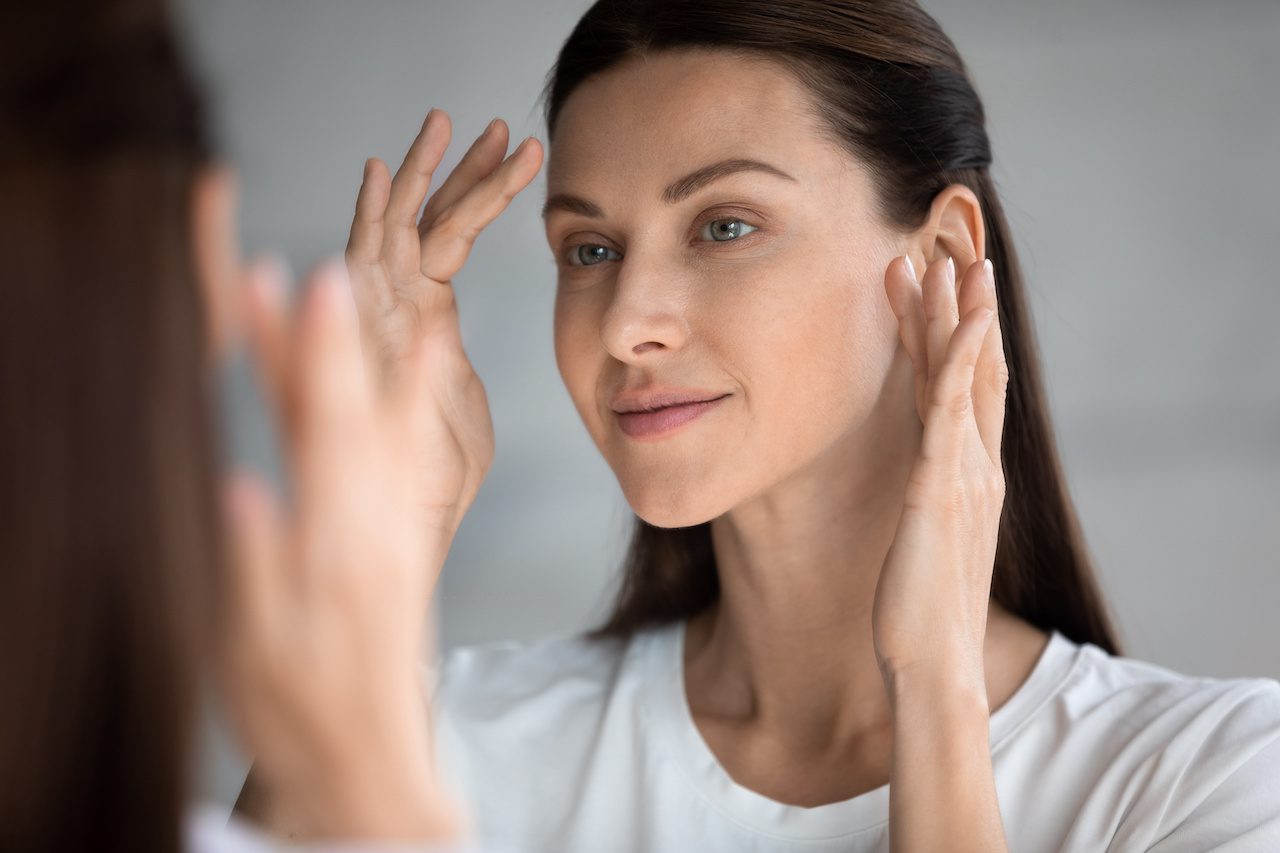 botox patient touching her jaw while looking in mirror